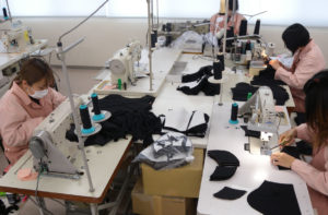縫製工場でミシンを使って仕事しているグループ